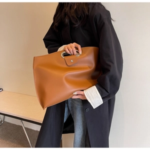 Close-up of caramel brown briefcase featuring oval metal handle and premium leather texture