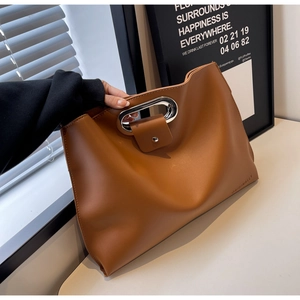 Detail of dark brown leather handbag featuring an oval silver metal handle and buckle closure