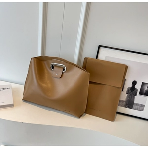 Close-up of khaki leather tote set with metallic handles and embossed brand logo