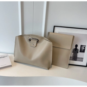 Detail of minimalist beige leather handbag set with silver metal oval handles and logo