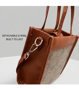 Detail of brown PU leather bag side with metal buckle and detachable shoulder strap