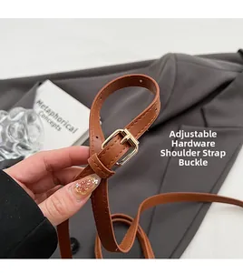Detail of adjustable shoulder strap with golden hardware buckle on brown leather bag