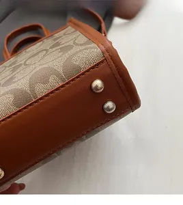 Detailed macro view of the handbag bottom featuring golden protective metal studs