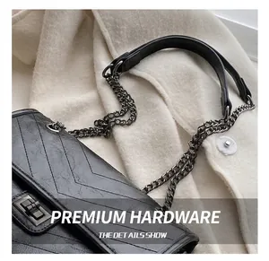 Détail d'un sac en cuir noir vintage avec coutures en V et fermoir en métal gris foncé