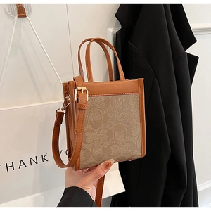 Close-up of brown plaid leather tote bag with jacquard fabric and gold hardware