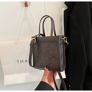 Detail of checkered pattern brown crossbody bag with gold hardware and top handles