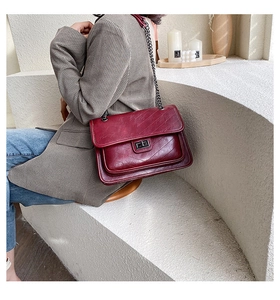 Détail d'un sac bandoulière matelassé rouge vin avec une chaîne et fermoir en métal
