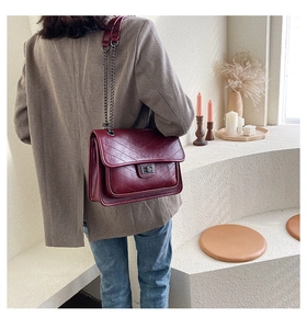 Détail du sac à bandoulière matelassé bordeaux avec chaîne porté par un mannequin