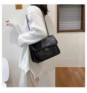 Détail du sac en similicuir noir surpiqué en V avec fermoir rectangulaire et bandoulière chaîne
