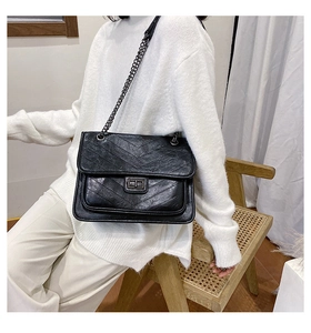 Détail d'un sac à chaîne noir matelassé en V avec fermoir rotatif au style vintage chic