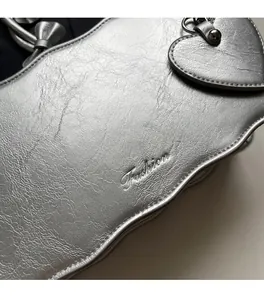 Detailed close-up of metallic silver bag texture with heart charm and embossed fashion logo