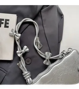 Detail of silver metallic bag featuring wavy edges and decorative silver bows on the strap