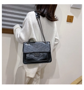 Vue latérale d'un sac à bandoulière matelassé noir avec coutures en V sur un mannequin