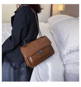 Vue détaillée du sac bandoulière marron matelassé avec surpiqûres en V et chaîne