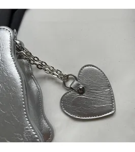 Close-up of a silver heart-shaped charm with pebble texture and metallic chain detail