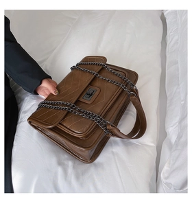 Détail du sac à bandoulière marron vintage avec surpiqûres en V et chaîne en métal