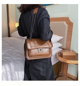 Détail du sac bandoulière marron vintage avec surpiqûres en V et chaîne en métal
