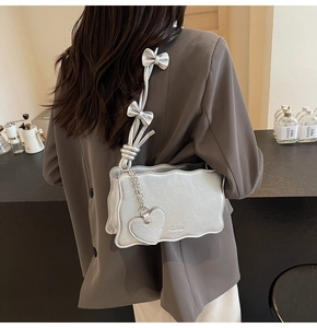 Detail of silver wavy-edge shoulder bag with metallic crinkle texture and heart charm