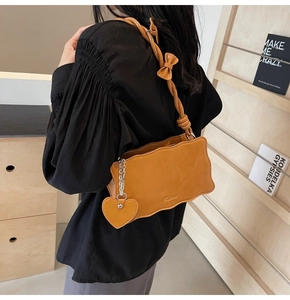 Detail of caramel shoulder bag featuring wavy edge design and bow strap decoration