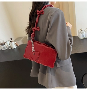 Detail of dark red leather shoulder bag featuring wavy edges and bow-knot strap details