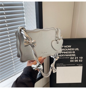 Silver shoulder bag with wave edge and bow straps detail featuring a heart charm