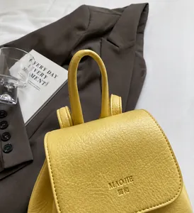 Detail of a yellow lychee-textured leather backpack with a sturdy round handle