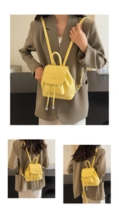 Detail of yellow pebbled leather mini backpack showing flap closure and drawstring design