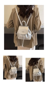 Detail of silver textured backpack featuring drawstring closure and metallic orb accents