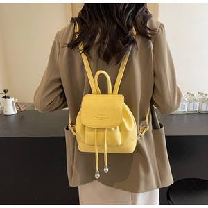 Detail of a bright yellow leather backpack with lychee texture and silver drawstrings