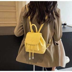 Detail of yellow mini backpack featuring drawstring closure and textured leather