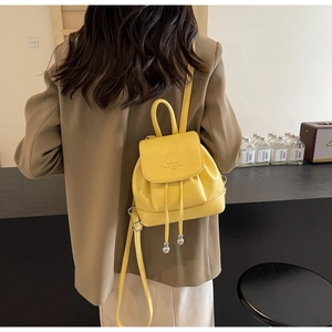 Detail showing the textured yellow leather texture and adjustable strap of the backpack