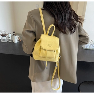 Detail of a bright yellow mini backpack with drawstring closure and adjustable straps