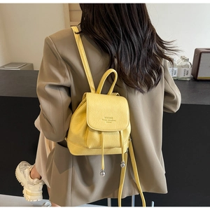 Detail of yellow minimalist backpack showing PU leather texture and drawstring closure