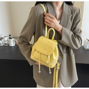 Close-up of a pale yellow mini leather backpack with lychee grain and drawstring flap