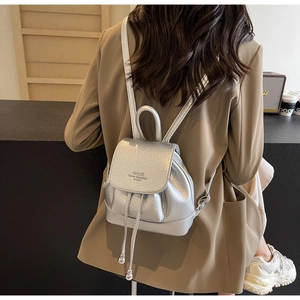 Silver metallic mini backpack with textured finish shown being worn by a model