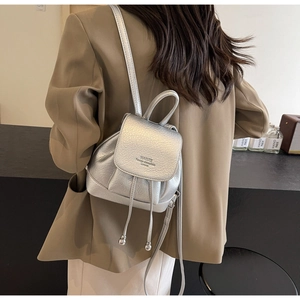 Detailed view of the silver metallic textured backpack with drawstring and flap closure