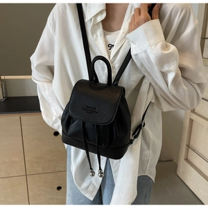 Close-up of black lychee texture backpack with drawstring closure and metal ball detail