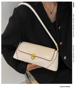 Detail of white baguette bag with brown trim and gold buckle on a tweed jacket