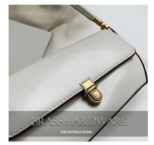Close-up of golden metal twist lock on a vintage white leather baguette handbag