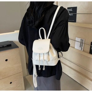 Side view of white pebble grain mini backpack showing drawstring and flap closure details