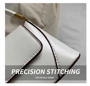 Close-up of brown edge paint and tight white stitching on a white leather baguette bag