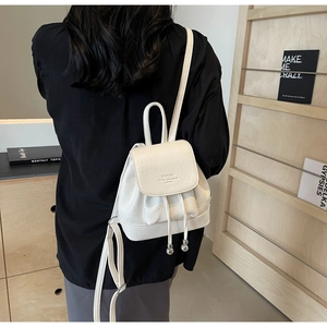 Close-up of white lychee pattern leather backpack with drawstring and metal bead detail