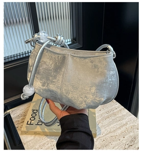 Detail of silver metallic cloud bag featuring unique clear sphere charms and knot handle
