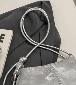 Detail of silver cloud bag featuring metallic rope strap and decorative clear bead