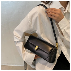 Detail of a vintage black leather baguette bag with a golden twist lock closure