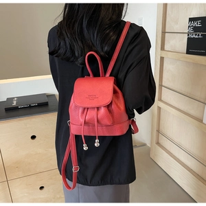 Close-up of red mini PU leather backpack with drawstring closure on model's back