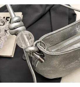 Detail of silver metallic textured bag with leather knot and transparent bead accent
