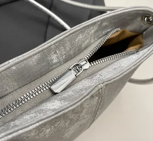 Detailed macro shot of a smooth silver metal zipper on a soft PU cloud-style crossbody bag