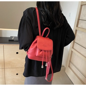 Close-up of red pebbled leather mini backpack with drawstring and metal ball detail