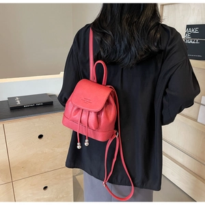 Detail of red leather mini backpack with silver ball charms and drawstring closure